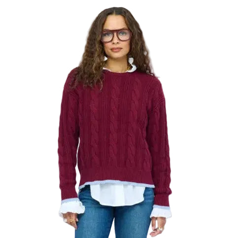 Kerri Rosenthal Maxwork Cable Pullover Sweater in Burgundy with contrast Imperfect Heart patchwork elbow patches, layered over a white poplin shirt with jeans.