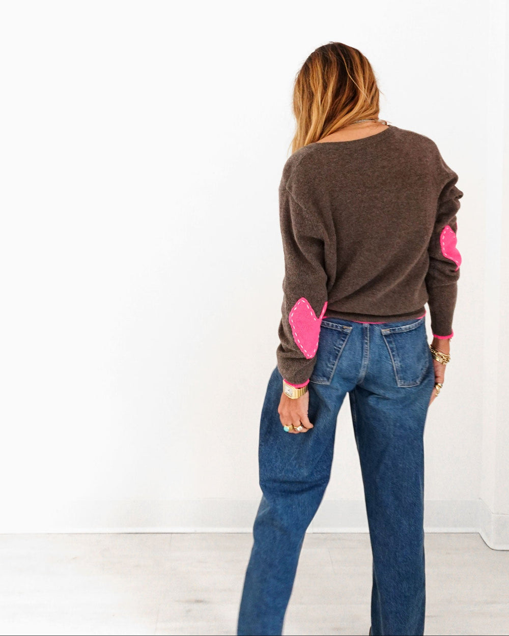 Kerri wearing the Patchwork Pullover Sweater in cocoa heather with pink heart elbow patches and jeans, back view