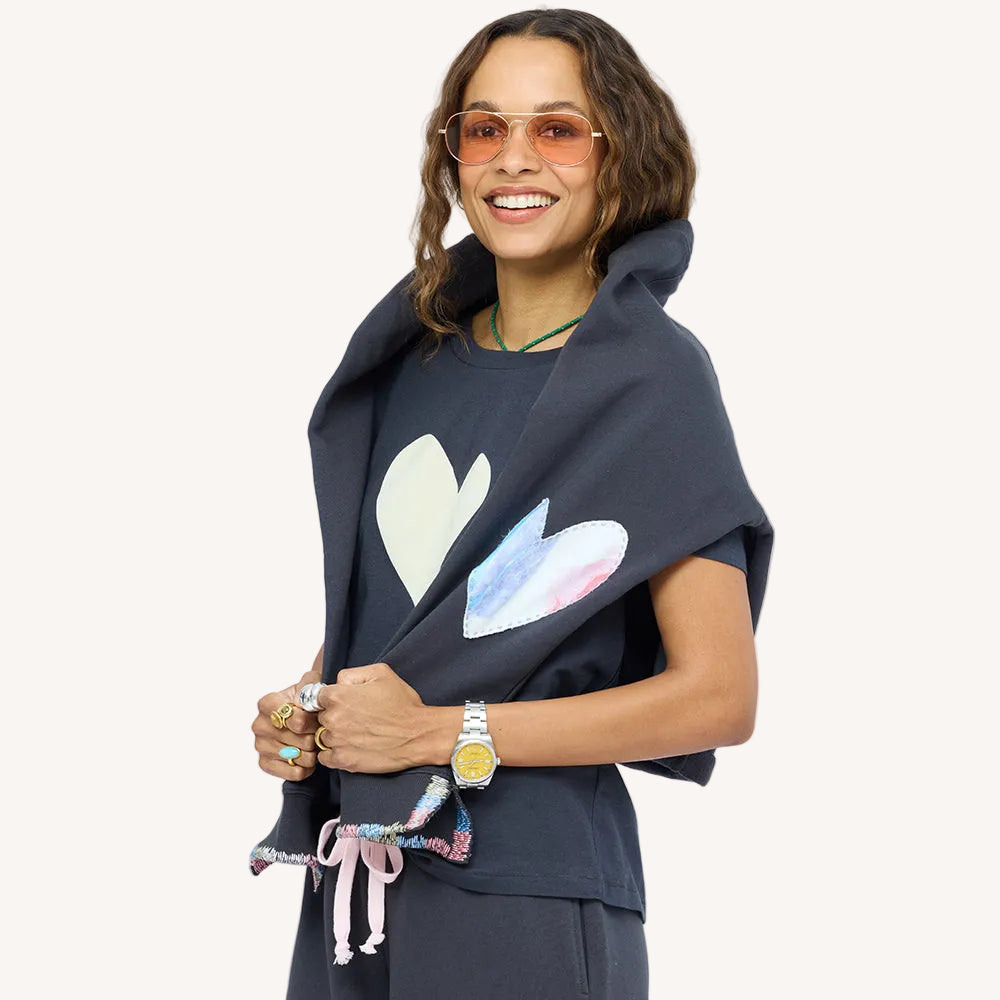 Woman wearing a charcoal sweatshirt with paint splat heart patch elbows and matching sweatpants, matching heart tee and sunglasses