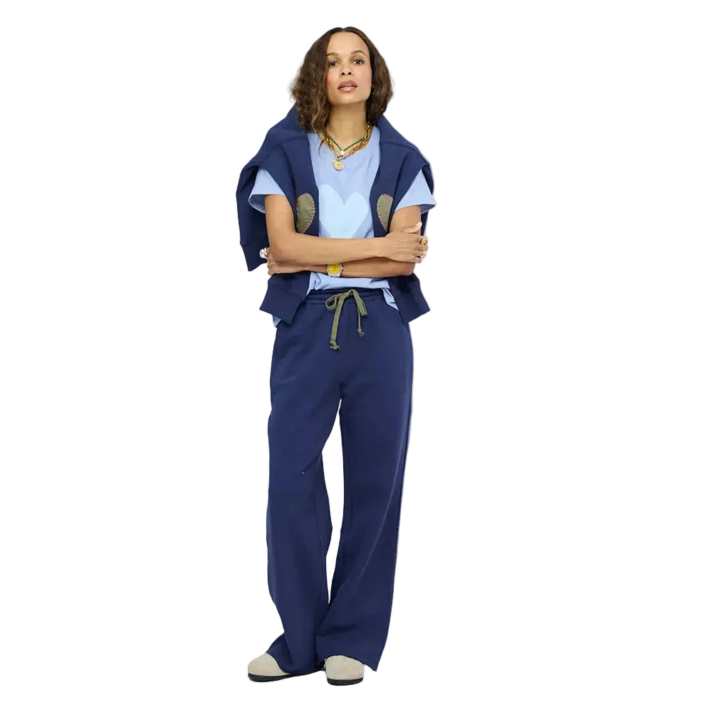 Woman wearing a Kerri Rosenthal light blue heart graphic tee under a navy sweatshirt, paired with navy wide leg sweatpants.