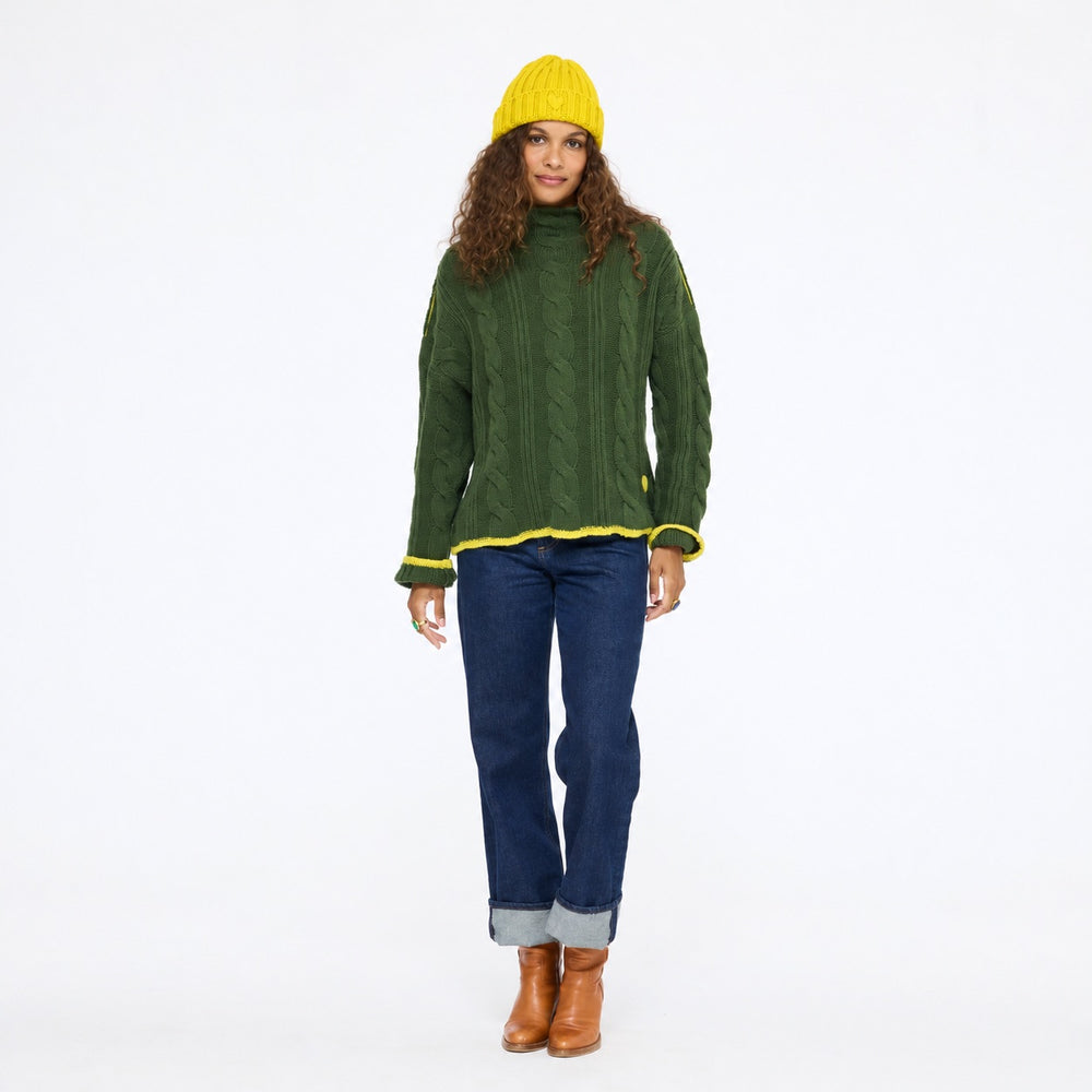 Model wearing the Hearth Sweater in spruce with the Winter Beanie in sunshine yellow, jeans, and tan boots, full length front view