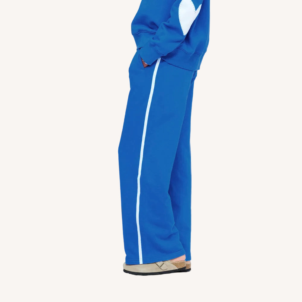 Close-up of blue track pants with white side stripe and matching sweatshirt with white heart elbow patches.