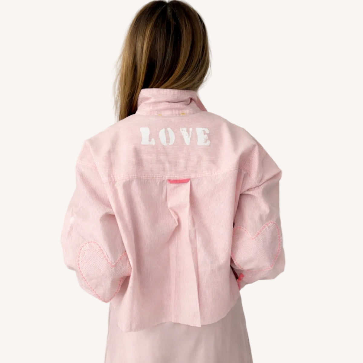 Back view of a pink striped shirt with 'LOVE' lettering and heart elbow patches.