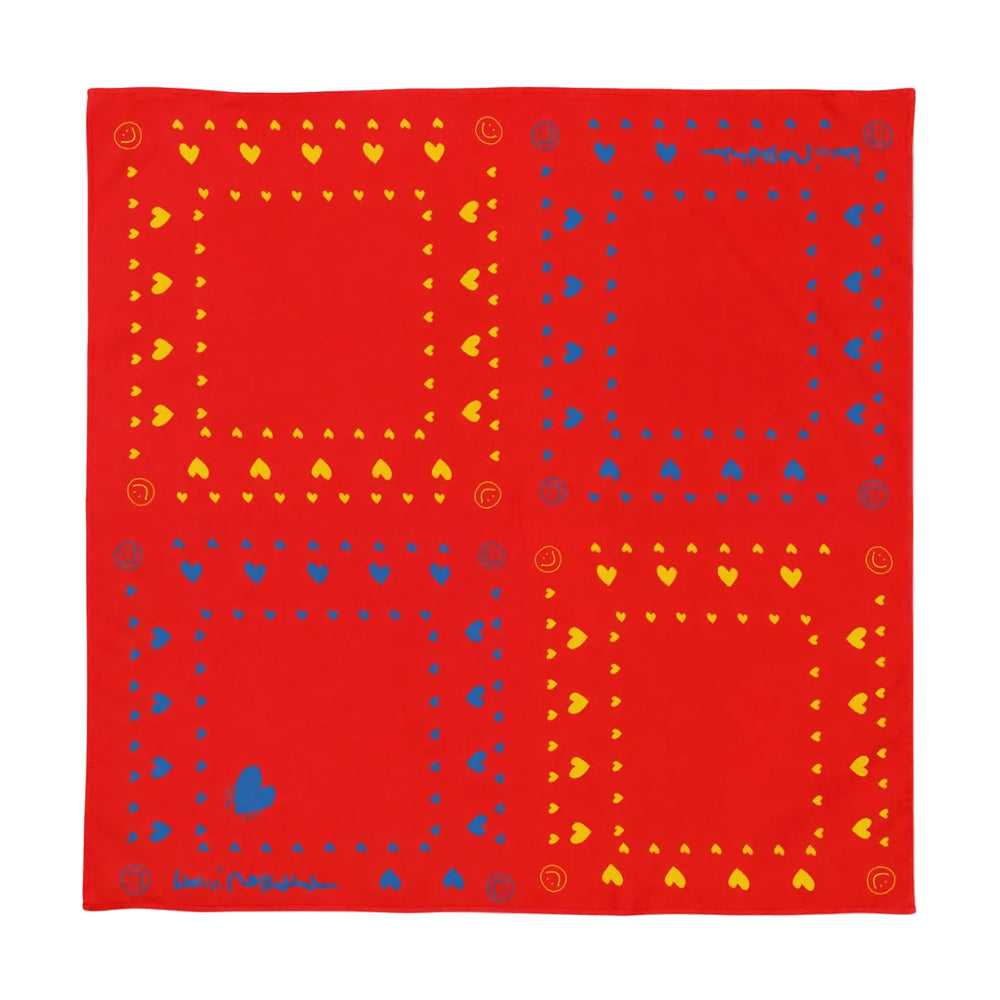 A square red bandana featuring a geometric pattern of four large panels, each bordered with yellow hearts and blue dots and small decorative motifs.