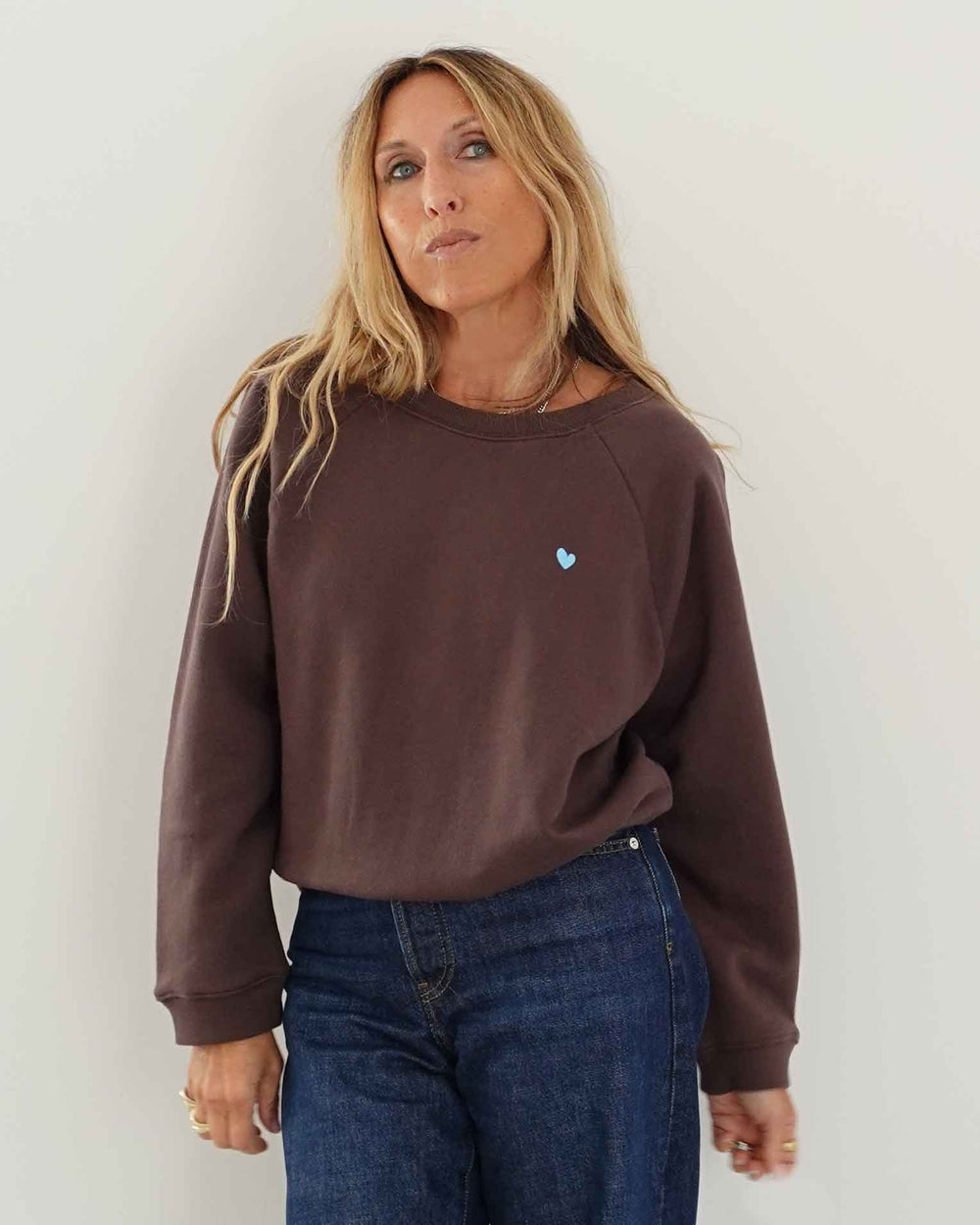 Kerri wearing True sweatshirt in brown with blue heart detail.