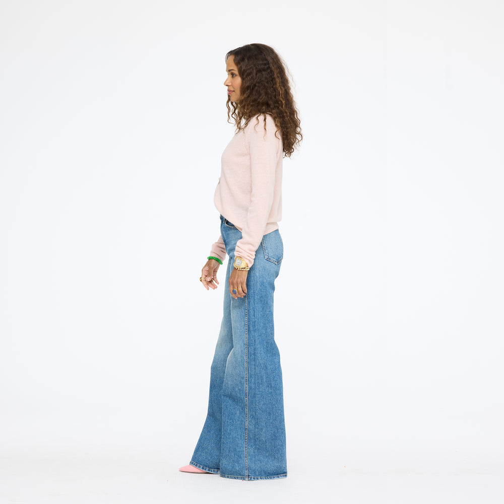 Model wearing the Pixie Sweater in pink with wide-leg jeans, side view