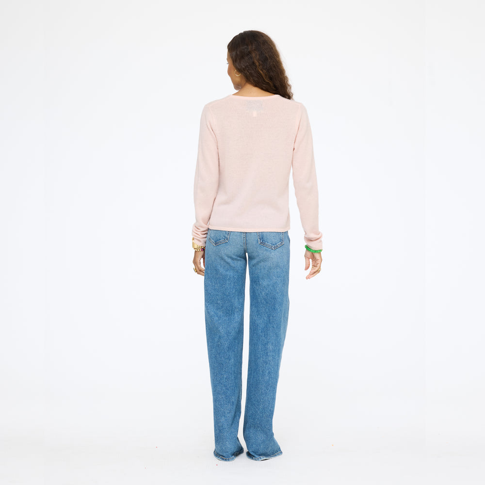 Model wearing the Pixie Sweater in pink with wide-leg jeans, back view