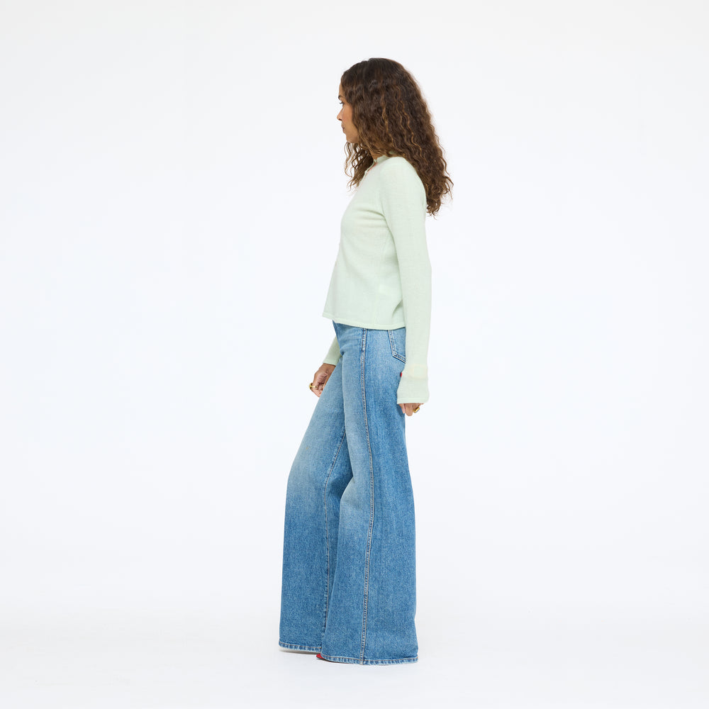 Model wearing the Pixie Sweater in pistachio with wide-leg jeans, full length side view