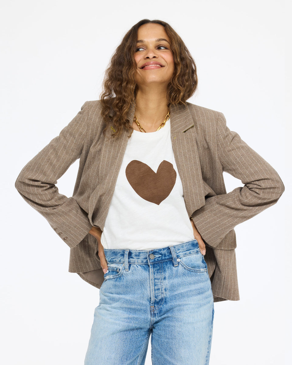 Model wearing the Long Sleeve Suke Imperfect Heart Tee in cream with a brown heart under the Workday Love Brigade Blazer in taupe and jeans, front view