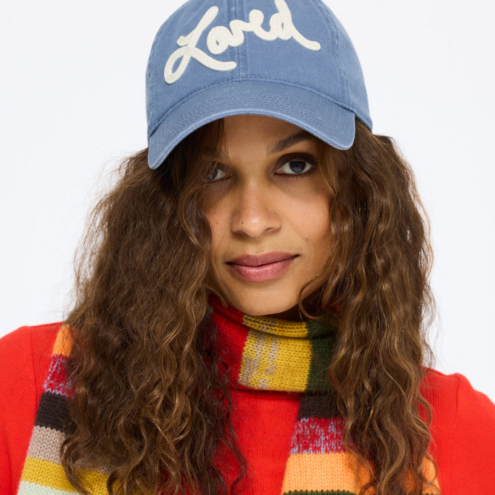 Close-up of the model wearing the Loved Baseball Hat in washed blue with a red top and the Fireside Scarf