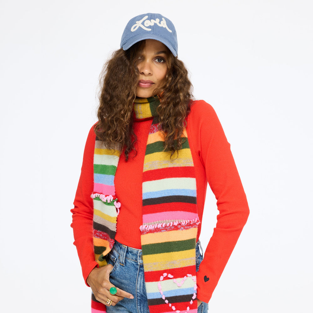 Model wearing the Loved Baseball Hat in washed blue with a red top and the Fireside Scarf, front view