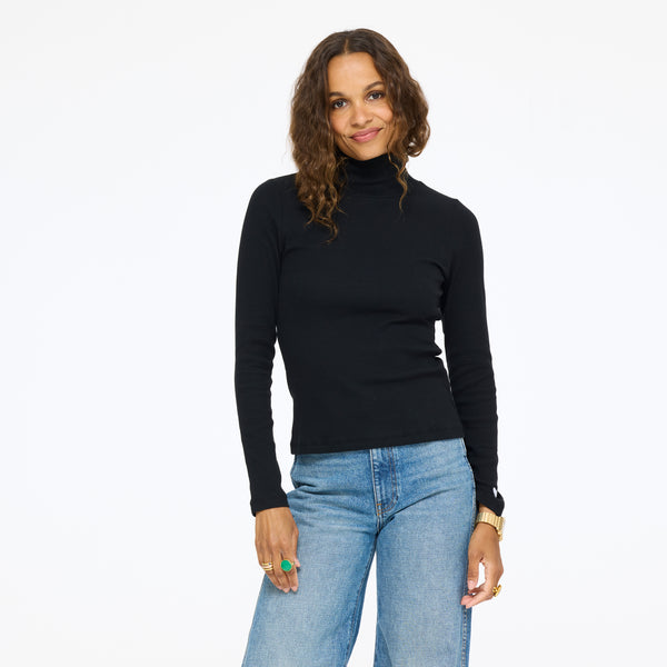 Model wearing the Mock Neck Rib Tee in black with wide-leg jeans, front view