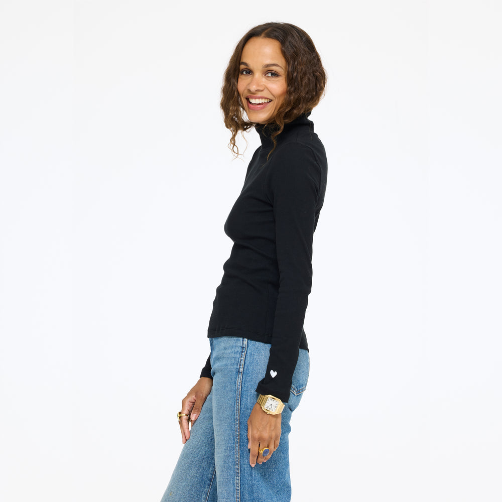 Model wearing the Mock Neck Rib Tee in black with jeans, side view