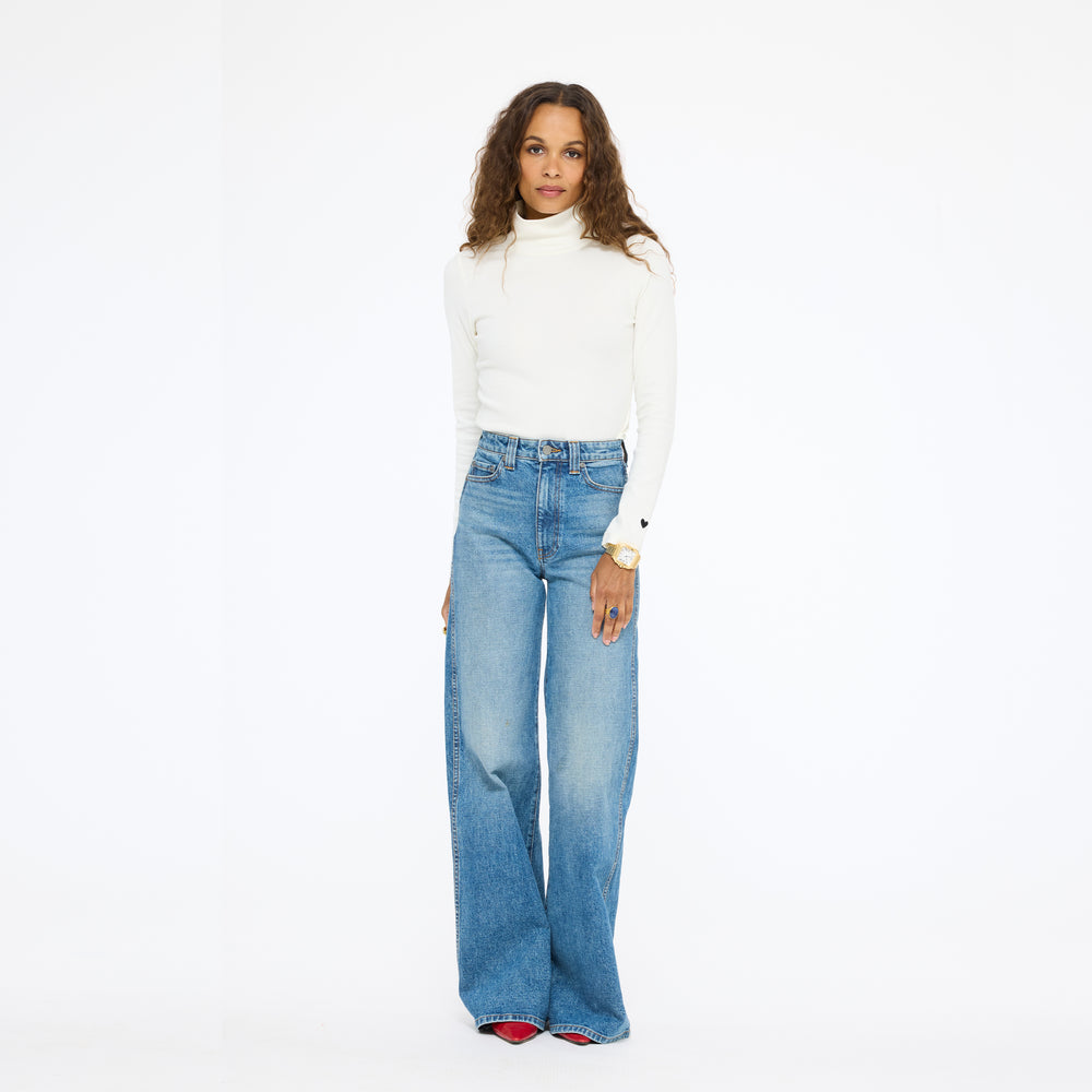 Model wearing the Mock Neck Rib Tee in cream with wide-leg jeans, full length front view