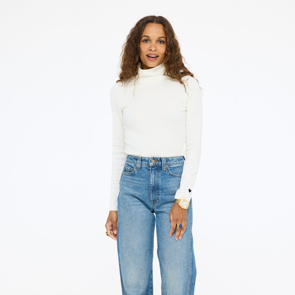 Model wearing the Mock Neck Rib Tee in cream with wide-leg jeans, three-quarter front view