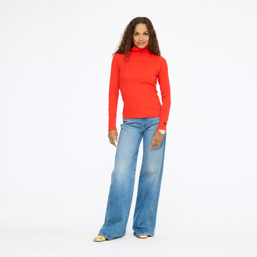 Model wearing the Mock Neck Rib Tee in red with wide-leg jeans, full length front view