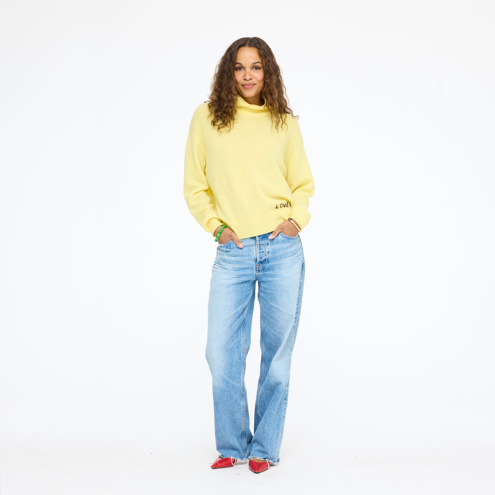 Model wearing the Mad Love Mock Neck Sweater in golden yellow with wide-leg jeans, full length front view
