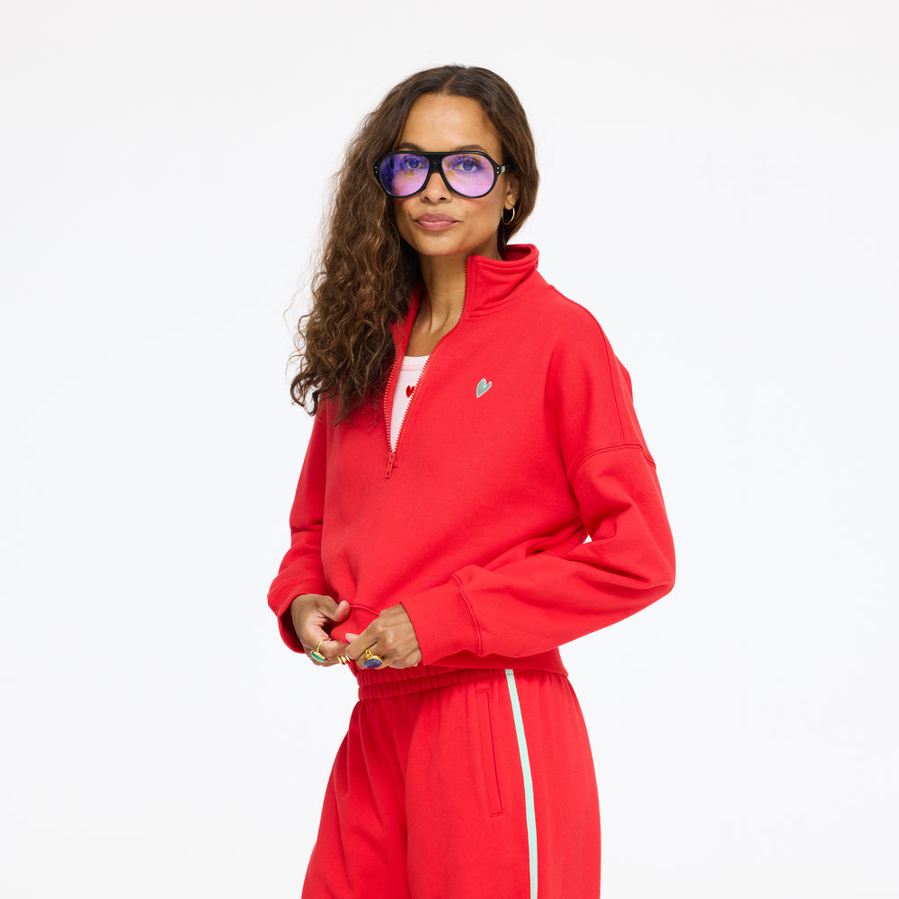 Model wearing the Sunday Quarter Zip Sweatshirt in red with sunglasses, upper body side view
