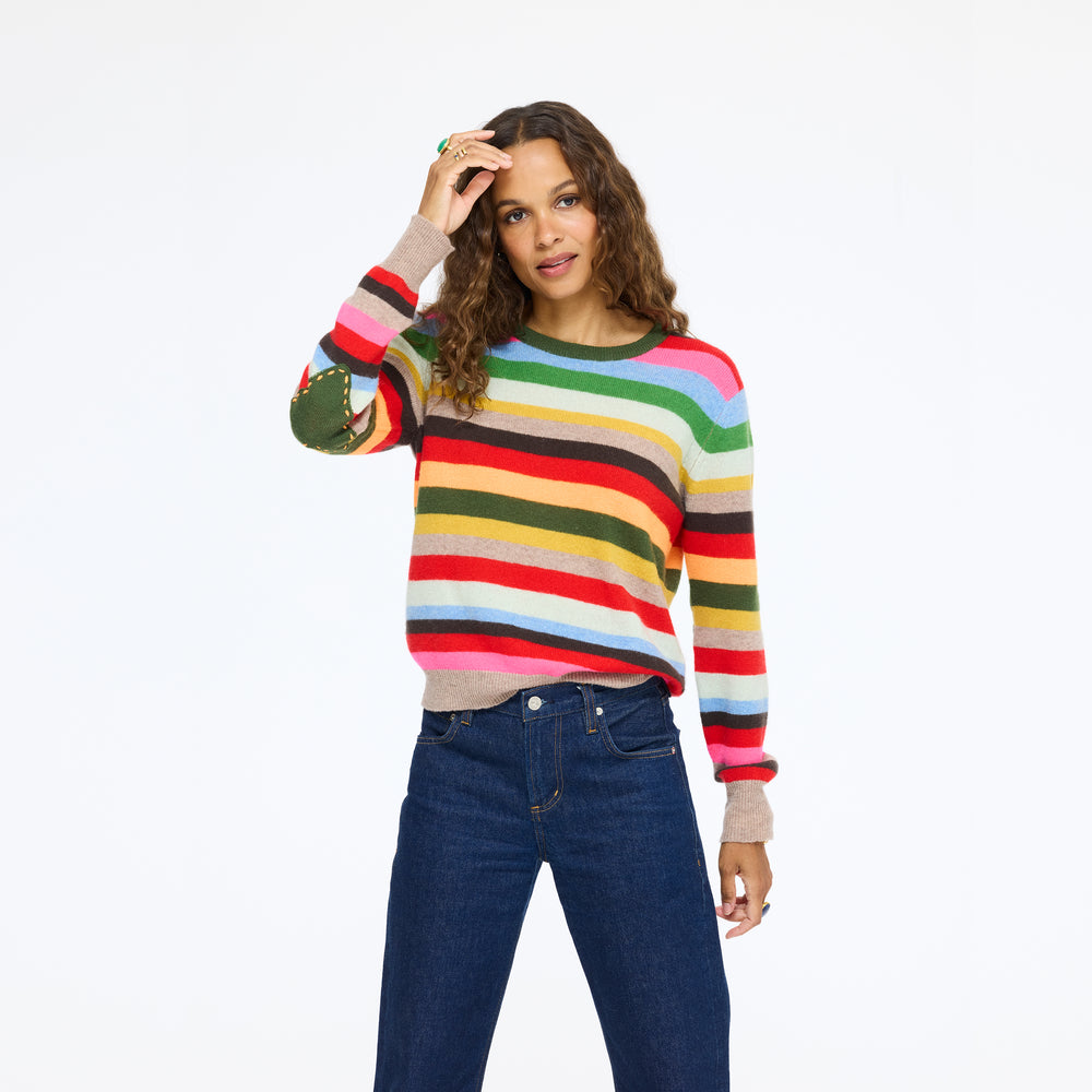 Model wearing the Patchwork Pullover Stripe Sweater in multicolor stripe with jeans, one hand raised to her head