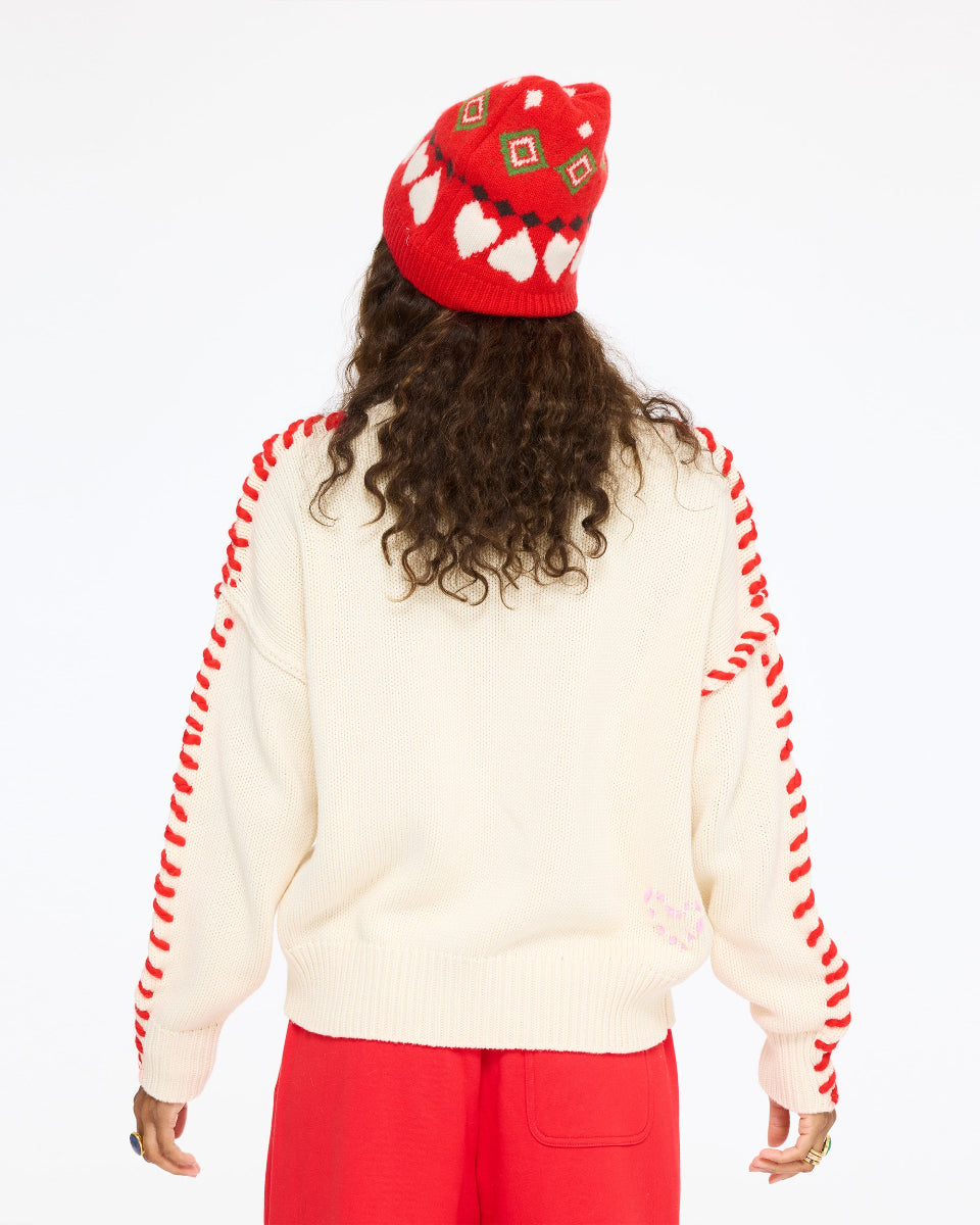 Model wearing the Love Big Sweater in cream with red stitching along the sleeves, the Weekend Palazzo in red, and the Rosey Beanie, back view