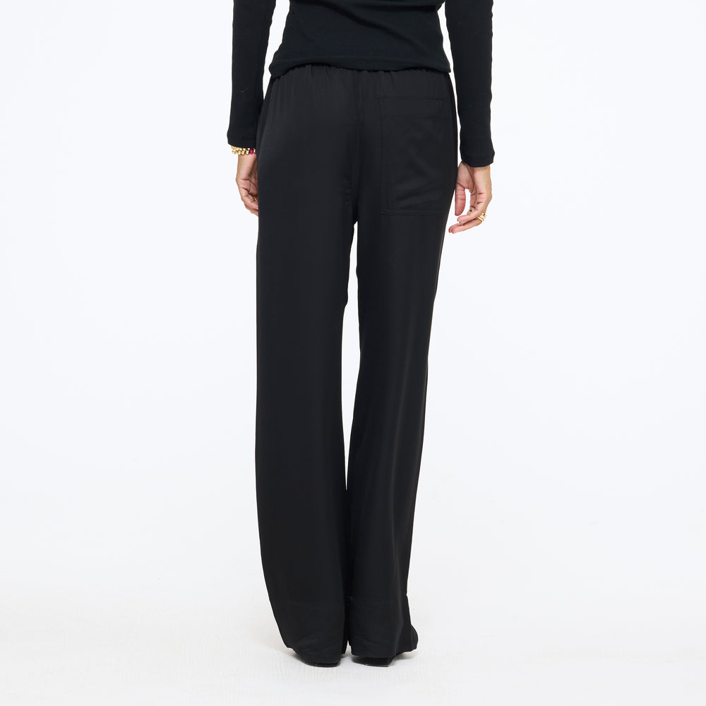 Waist-down front view of the Coast Pant in black with a black top