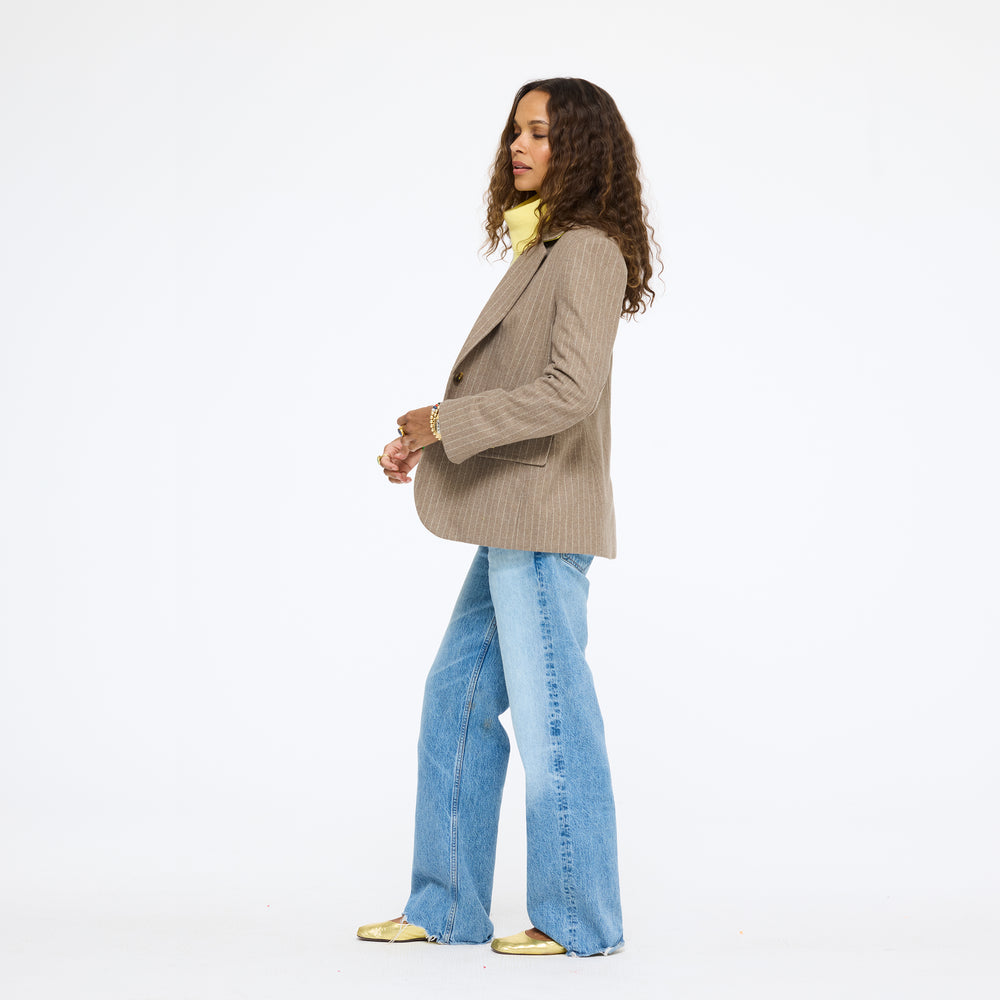Model wearing the Workday Love Brigade Blazer in taupe pinstripe with jeans, full length side view