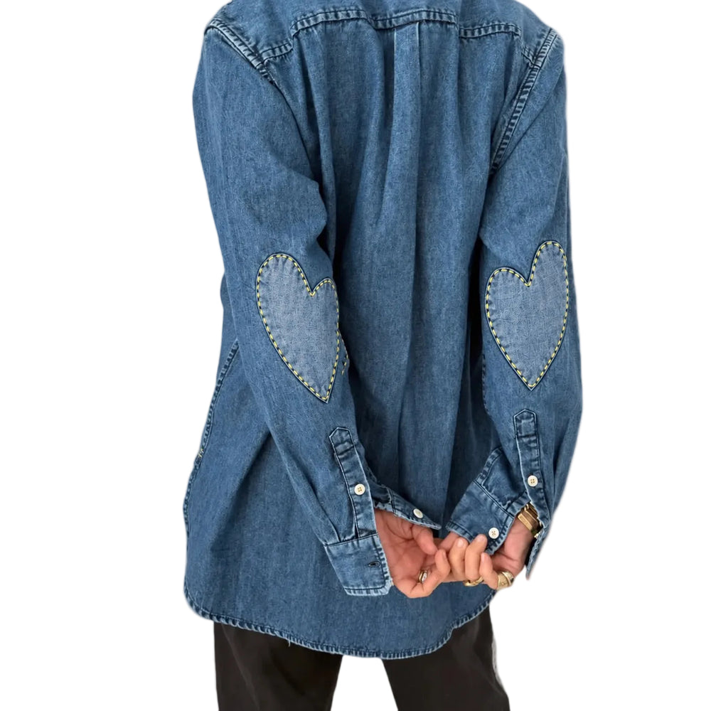 Close-up of the heart elbow patches on the Mia Denim Shirt in washed denim, worn with black pants, back view
