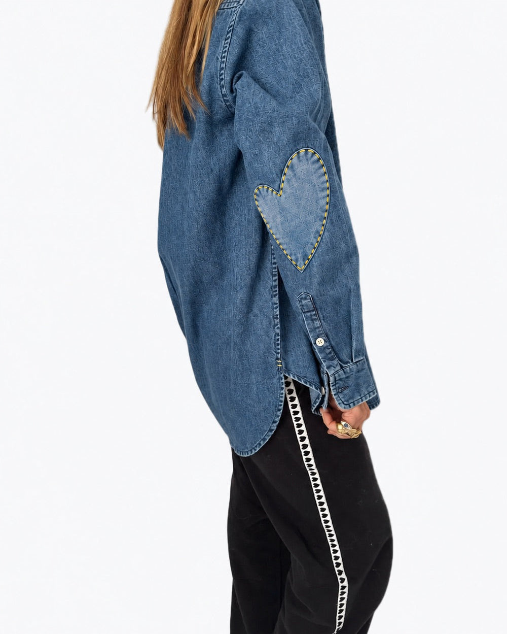 Side view of the Mia Denim Shirt in washed denim with a heart elbow patch, worn with black pants