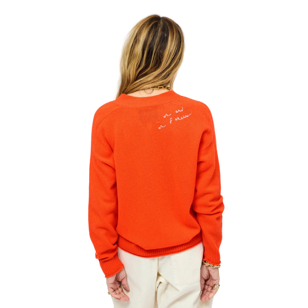 Back view of woman wearing a tomato cardigan with a gold jewelry, natural white drawstring pants, and tomato heels. Womens clothing by Kerri Rosenthal