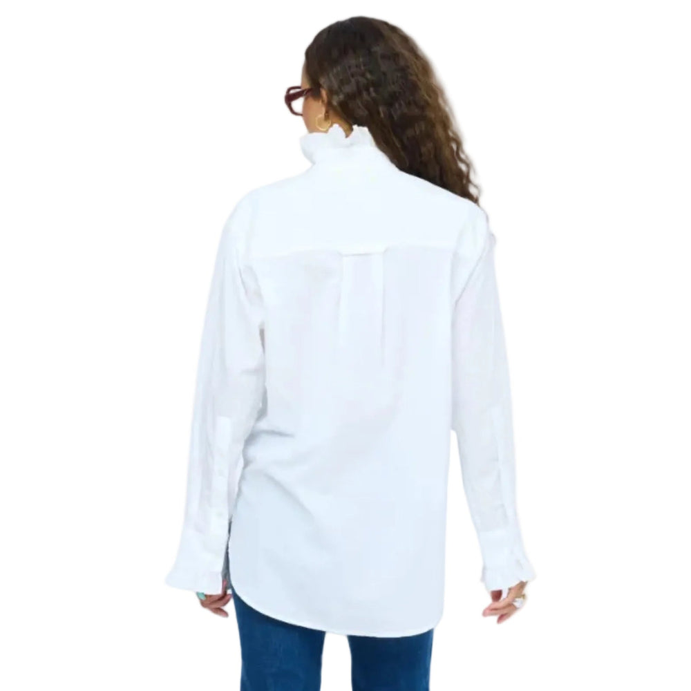 Full-length  back view of model wearing dark red glasses, white ruffle-collar shirt, blue jeans, and burgundy ankle boots, standing with one hand in pocket.