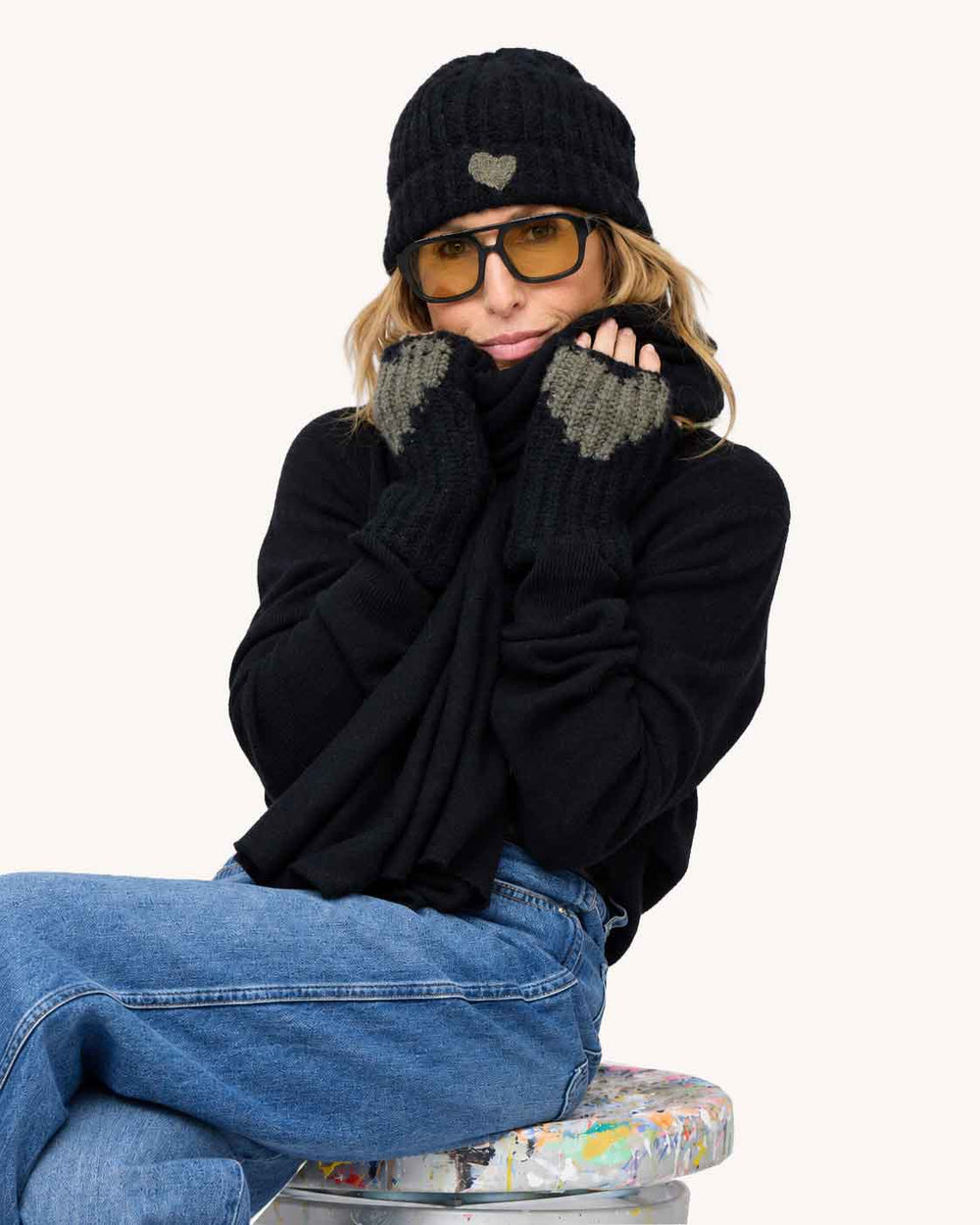 Kerri wearing black smittens with grey heart detail, cashmere wrap and winter hat in black with grey heart detail.