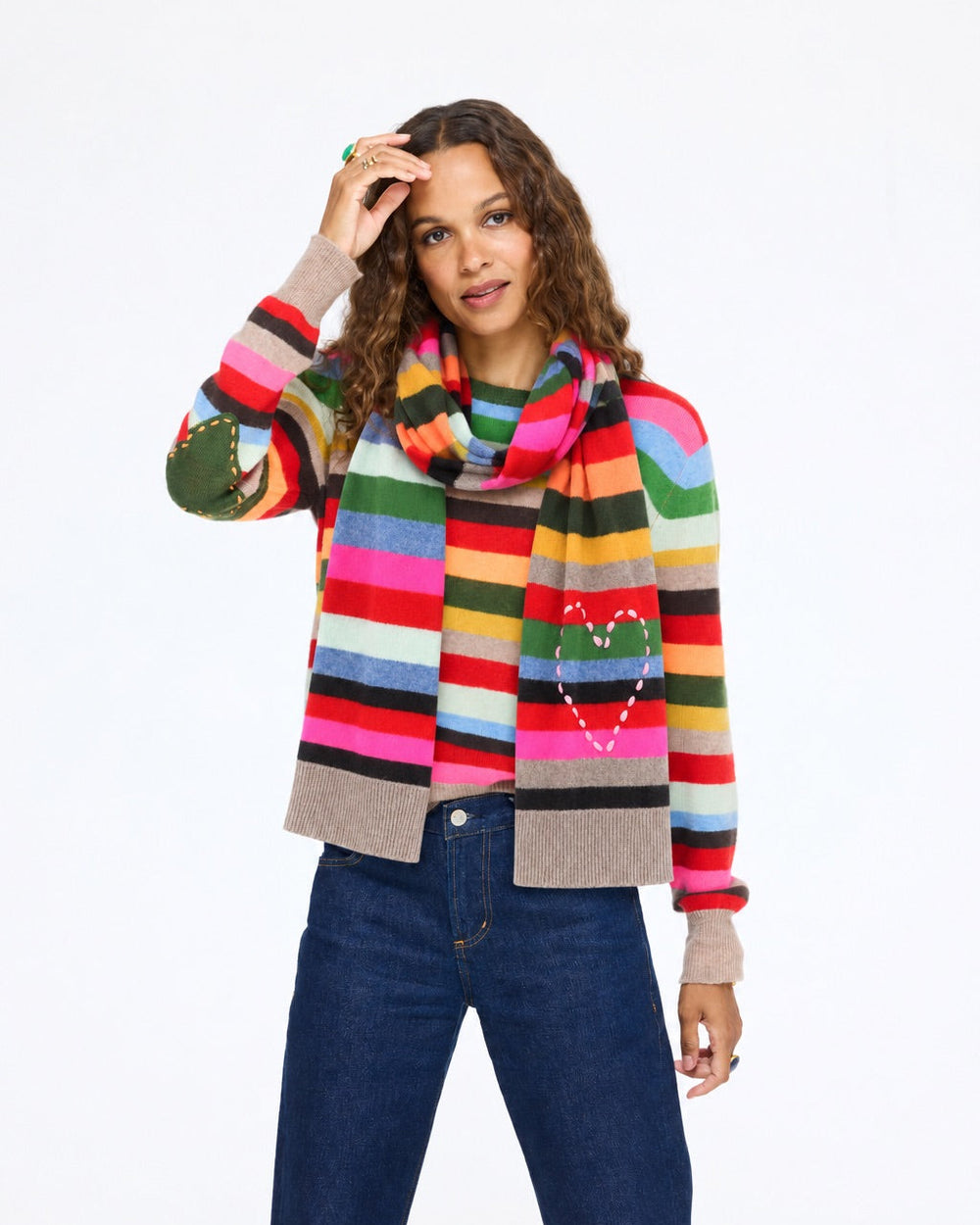 Kerri wearing the Fireside Scarf with the Patchwork Pullover Stripe Sweater and jeans, hand at her head