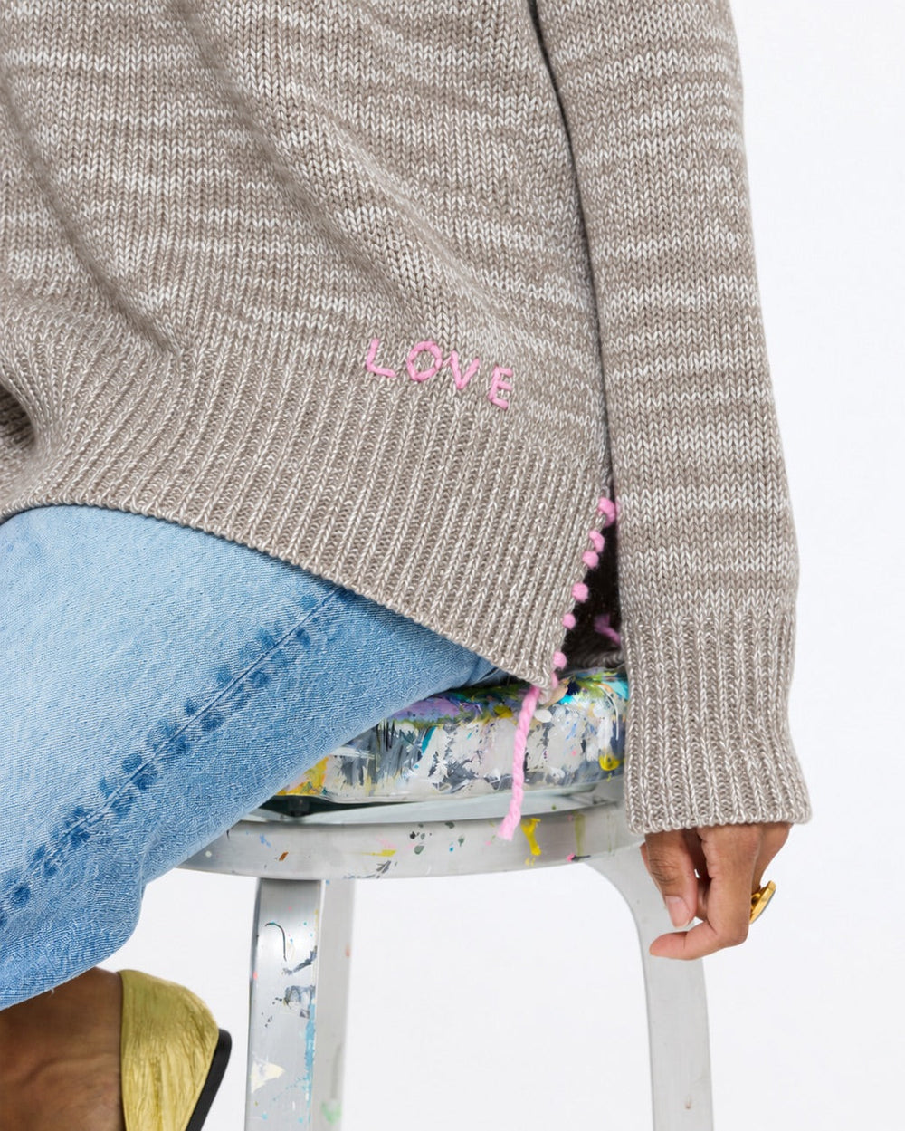 Close-up of the Lovey Heart Pullover in taupe showing the knit texture and side hem slit, with jeans