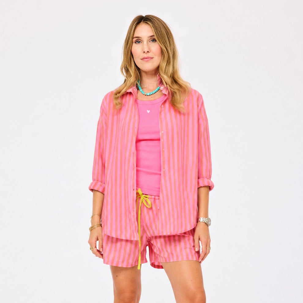 Women's pink and orange striped oversized button-down shirt and shorts set.