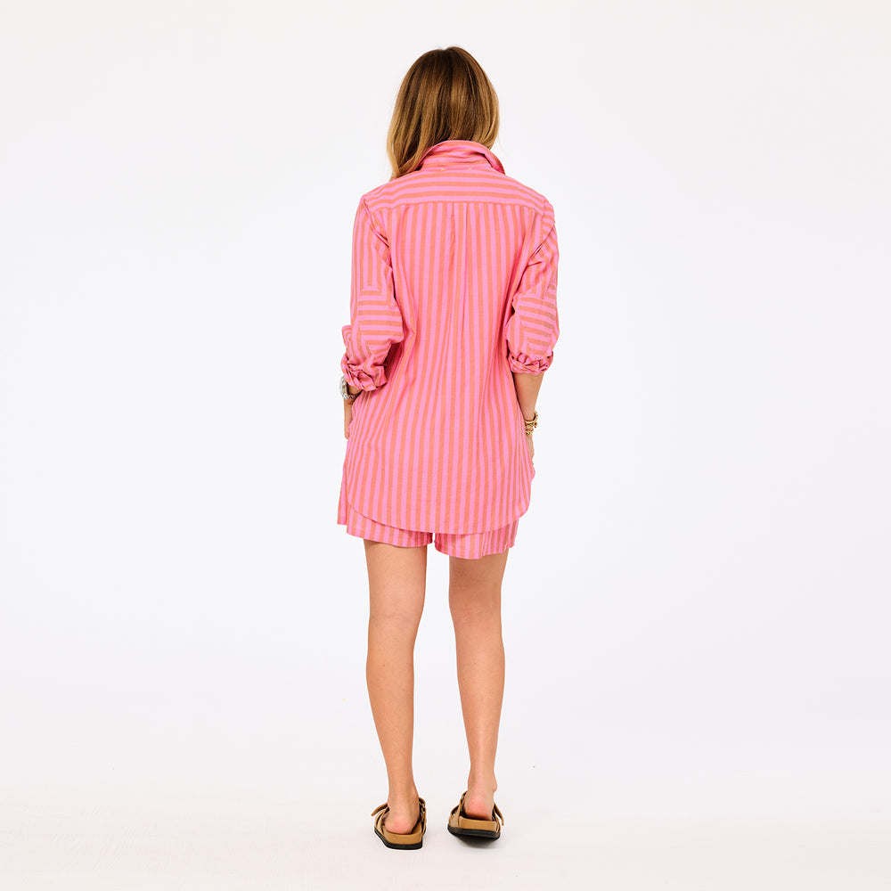 Back of women's pink and orange striped oversized button-down shirt and shorts set.