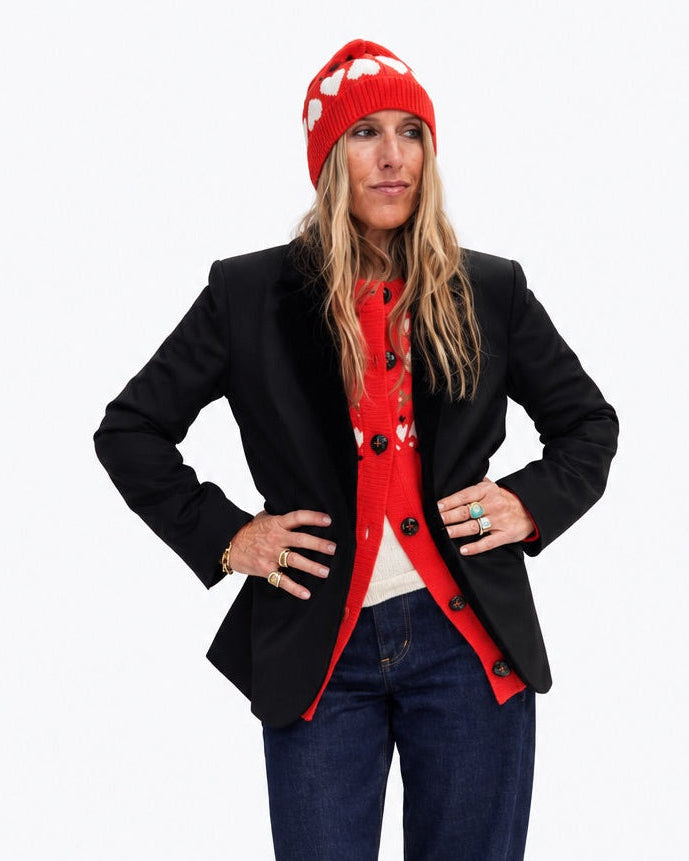Kerri wearing the Rosey Beanie in red with a black blazer, a red top, and jeans, hands on her hips, front view