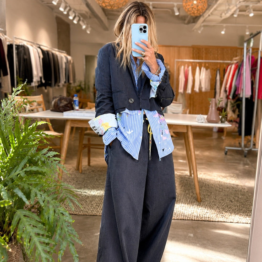 Mirror selfie of a woman wearing a blue striped art-print shirt layered under a navy blazer with matching wide-leg pants.