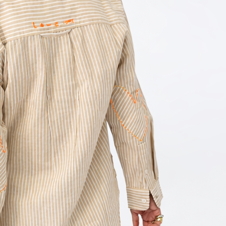 Woman wearing a beige striped shirt with a visible brand logo on a white background